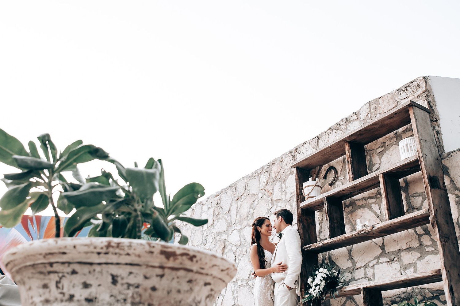 Romantic wedding moment captured from above with decorative stone planter and rustic wooden backdrop.