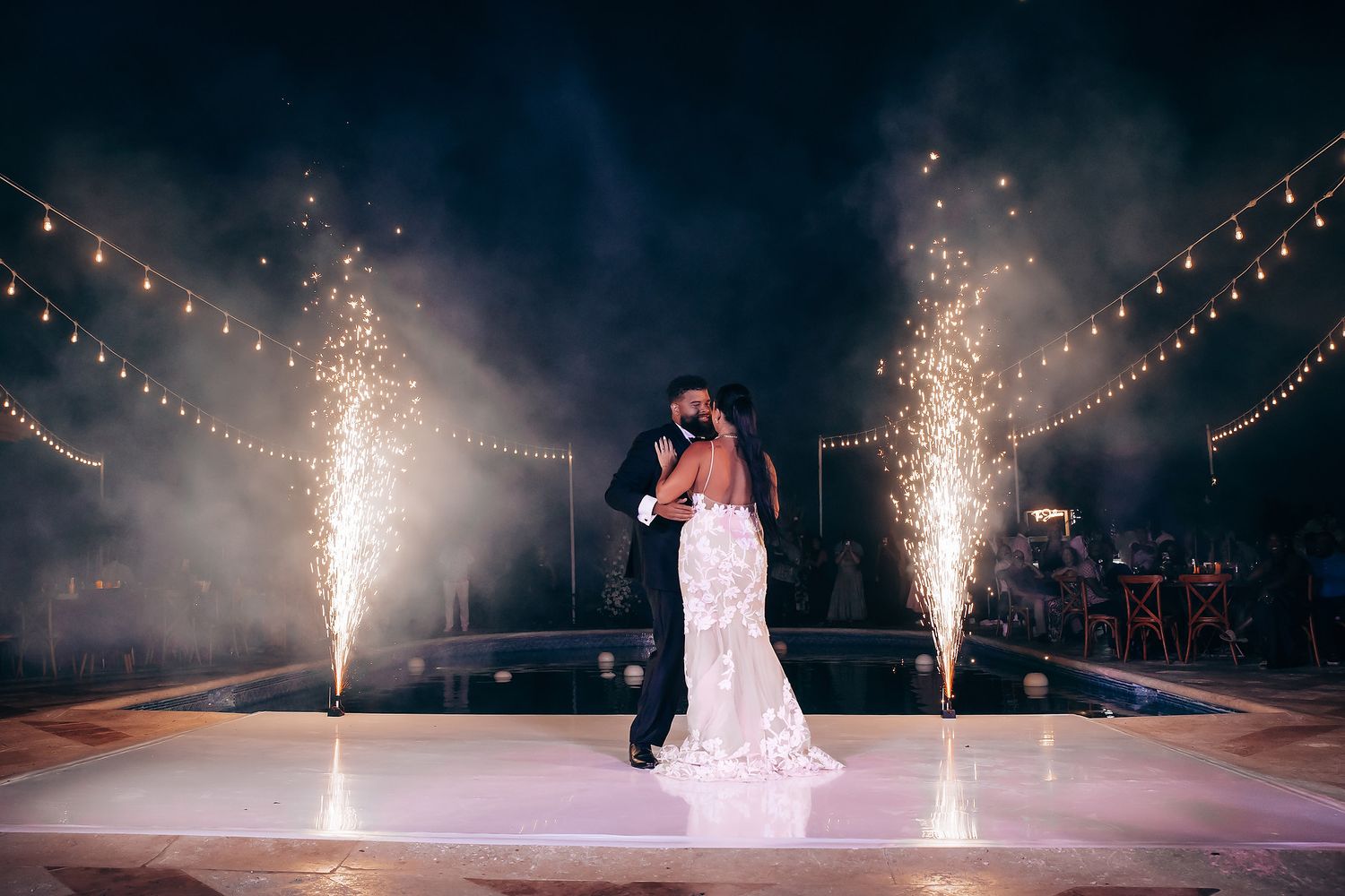 Sparkler fountains create a magical atmosphere during a nighttime wedding dance.