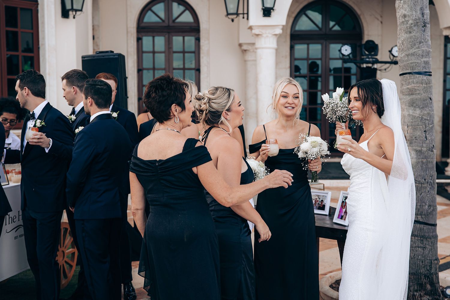 A group of wedding guests dance and celebrate together during an elegant indoor reception.