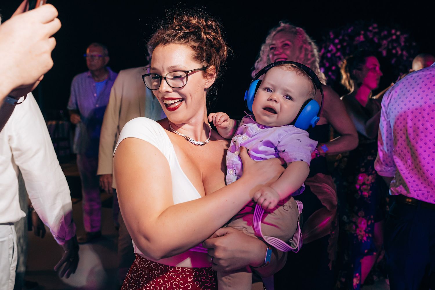 A parent and baby share a joyful moment together on a crowded dance floor.