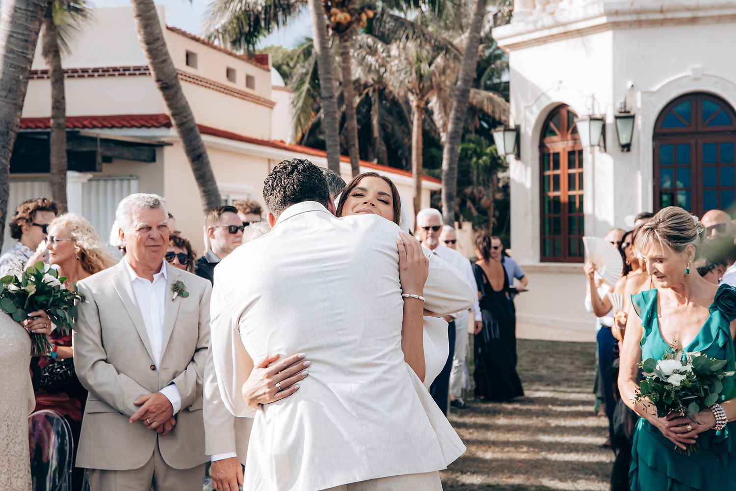 Wedding guests embrace in a series of emotional moments during an outdoor celebration at a Spanish-style venue.
