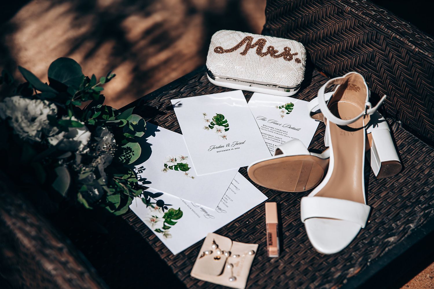 Wedding invitation suite with elegant calligraphy and floral details laid out on dark textured surface.