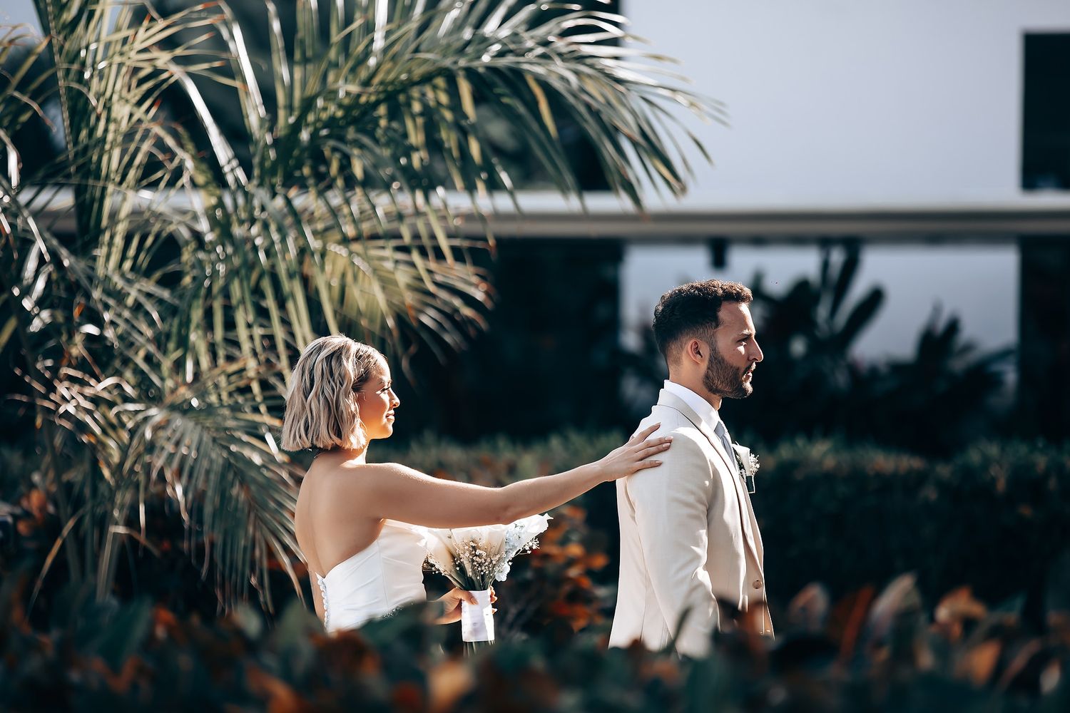 Outdoor wedding celebration with palm trees and guests raising glasses.