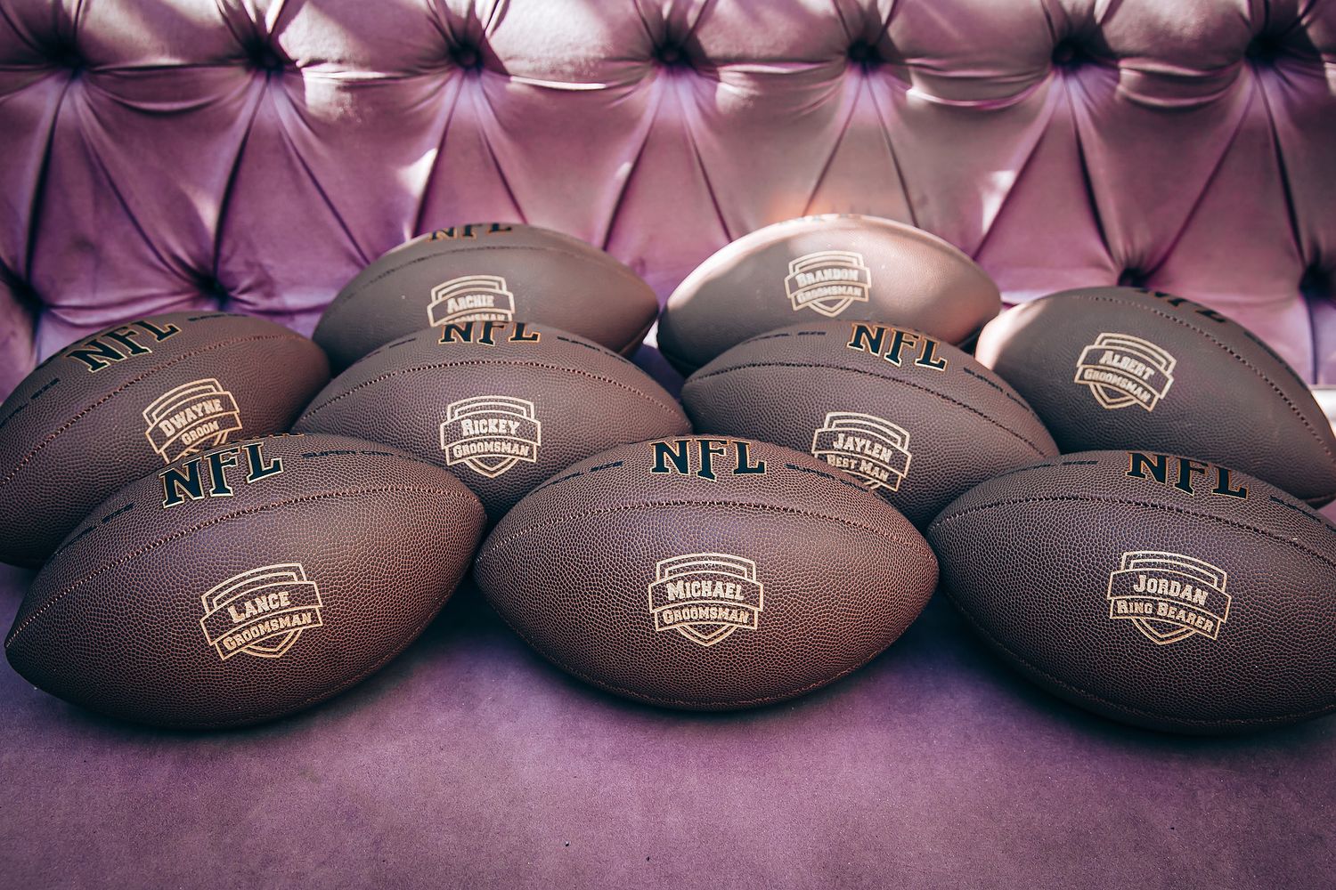 Row of official NFL footballs arranged on a dark surface with purple lighting effects.