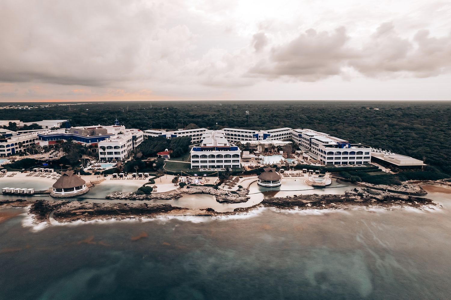 Aerial panoramic view of beachfront resort and coastline with white buildings.