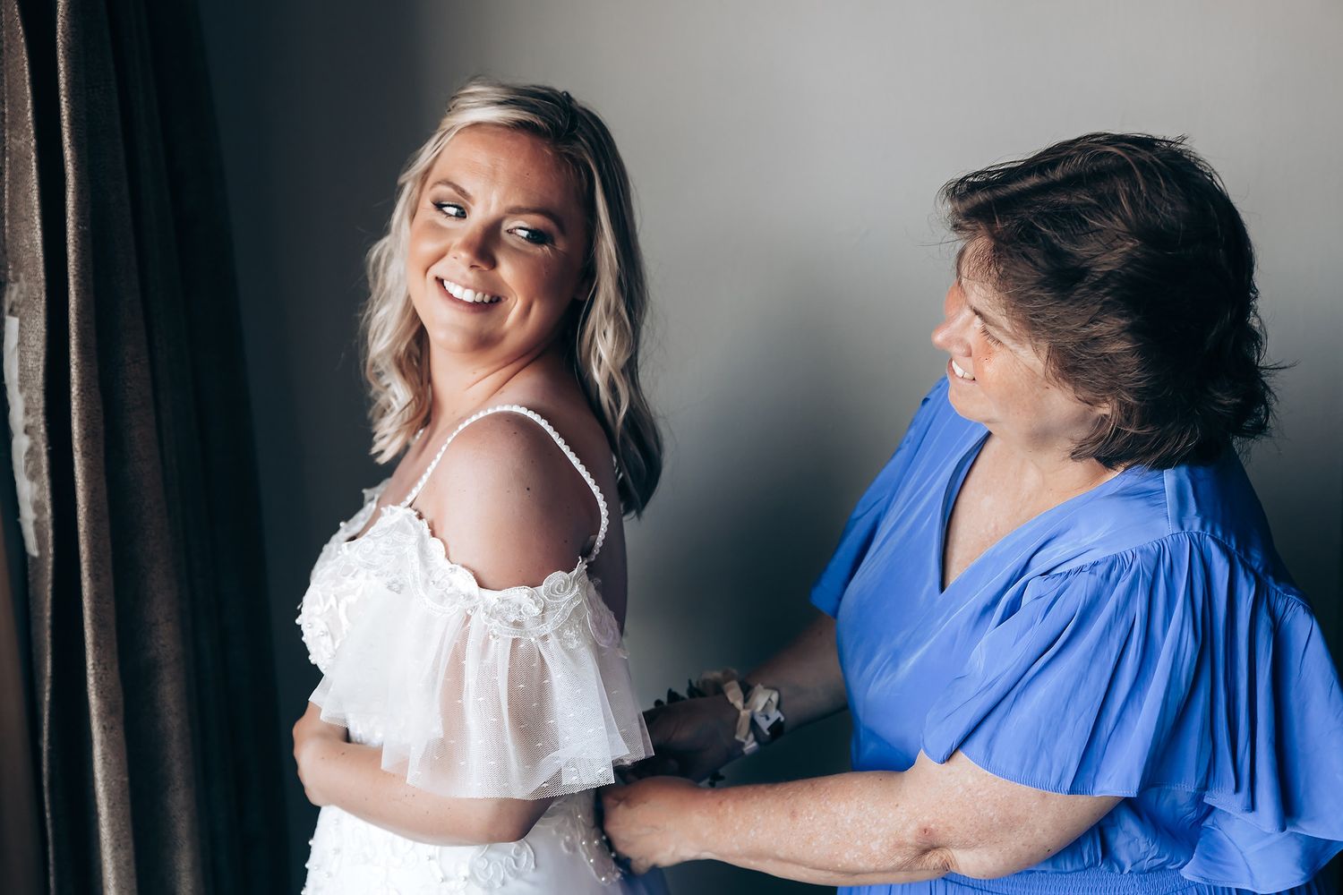 A couple shares joyful moments in a bright indoor setting wearing white and blue outfits.