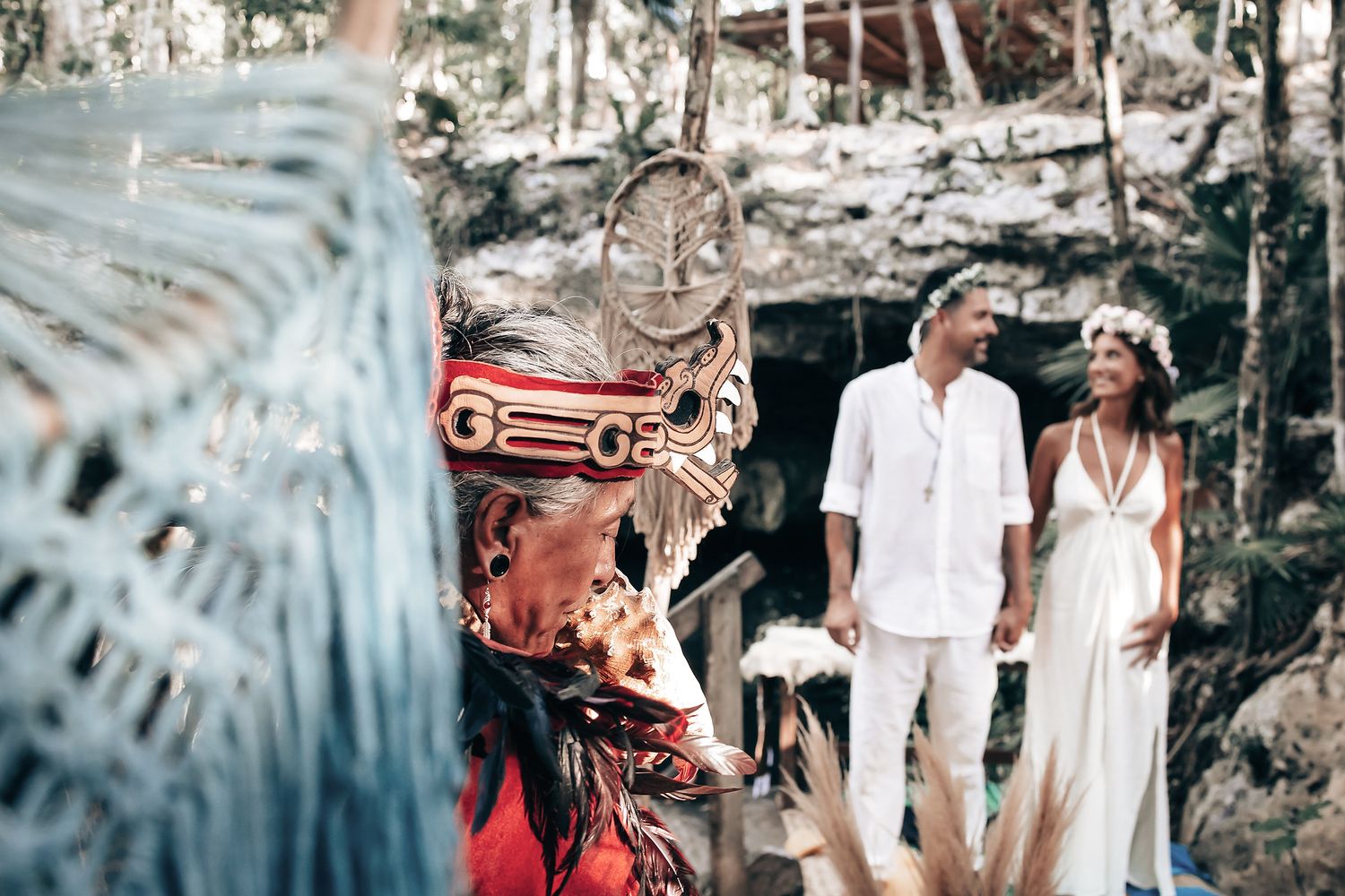 A couple exchanges vows or rings during a wedding ceremony in a natural, scenic setting.