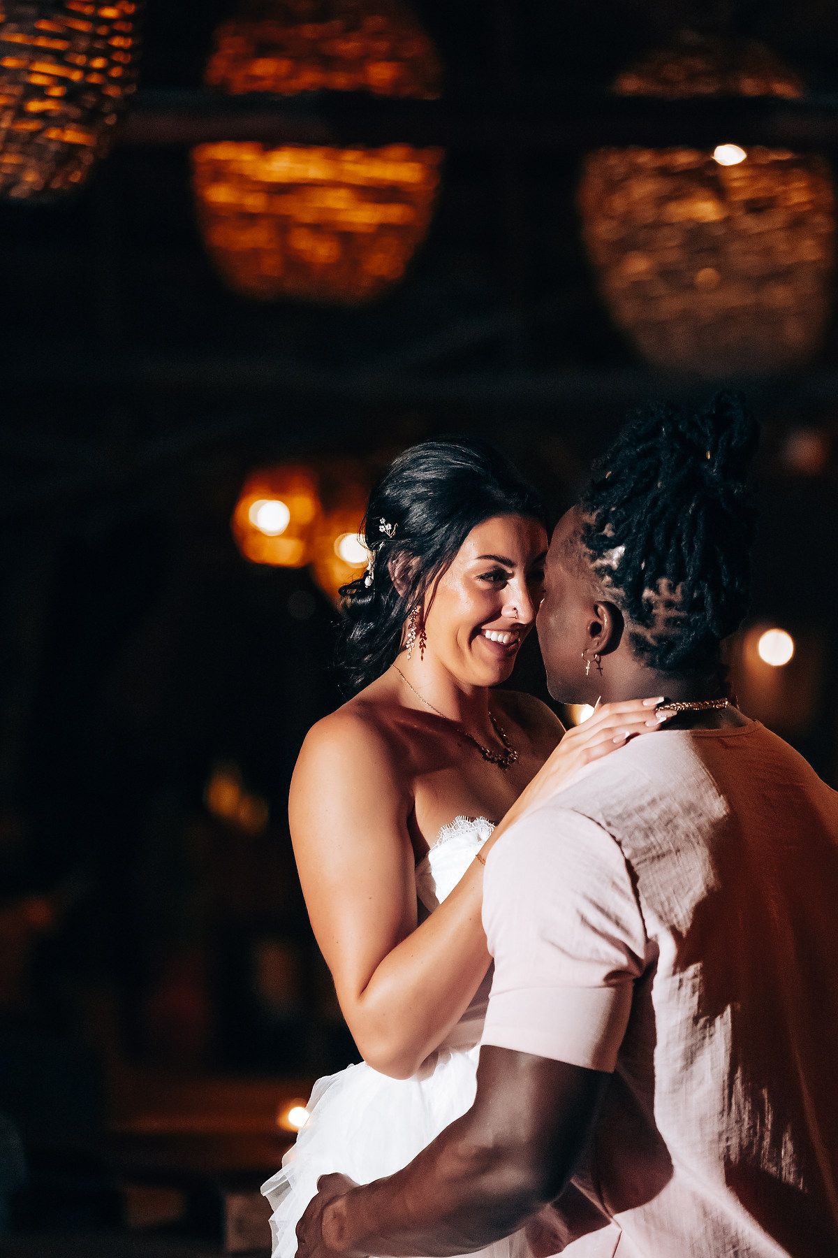 A couple shares a tender moment at their wedding ceremony, illuminated by warm lighting.