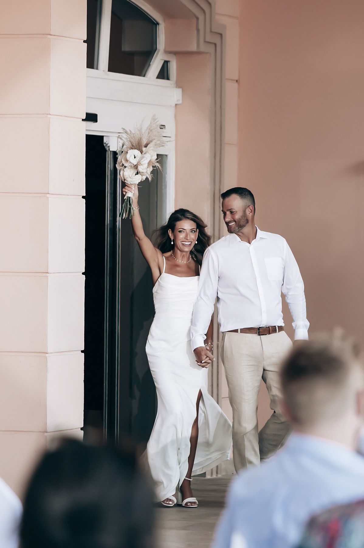 A bride and groom walking down an aisle at what appears to be an outdoor wedding or event.