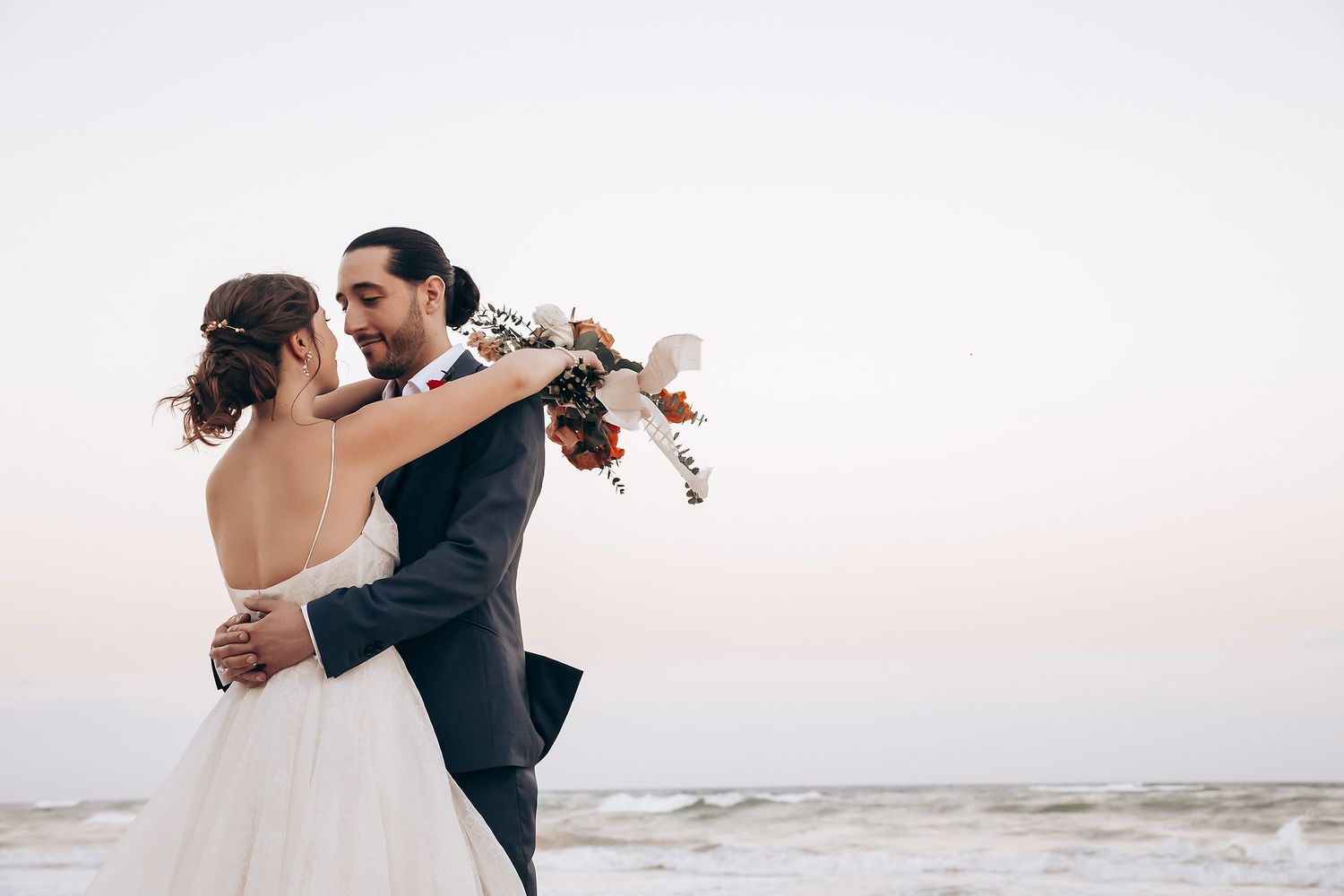 Romantic sunset beach wedding photos with soft lighting and ocean backdrop.