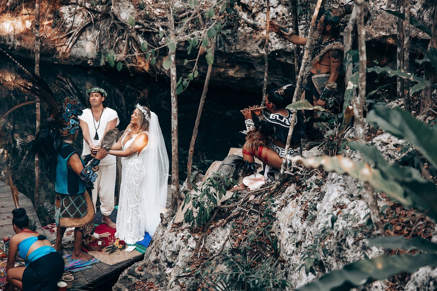 Wedding guests gather in a natural garden setting with tropical plants and string lights creating ambiance.