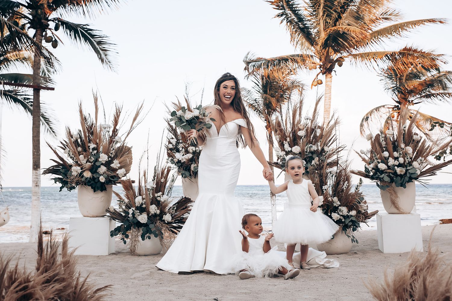 Romantic beach wedding photoshoot with palm trees and tropical decor at sunset.