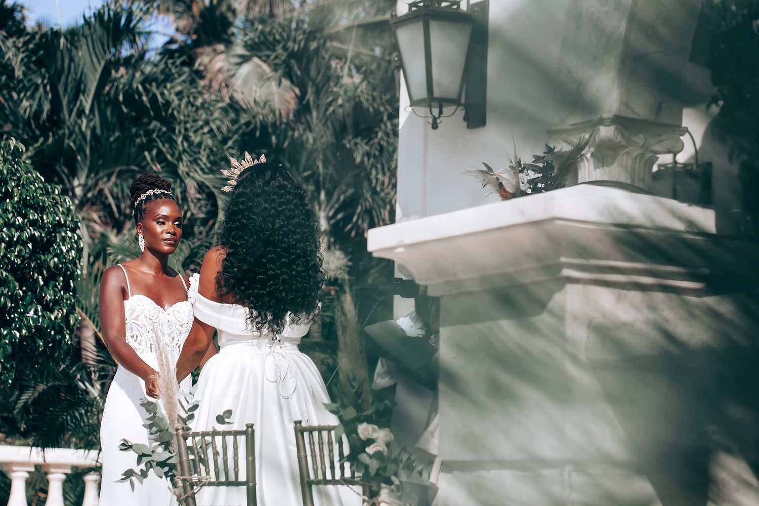 Elegant wedding photoshoot with flowing white dresses in a tropical outdoor setting.