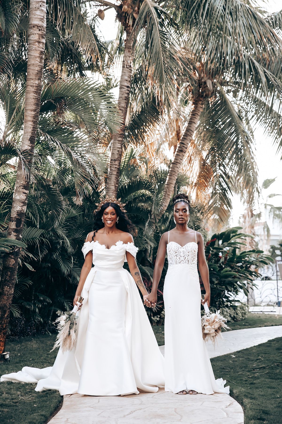 Beautiful wedding party posing among palm trees in matching white gowns.