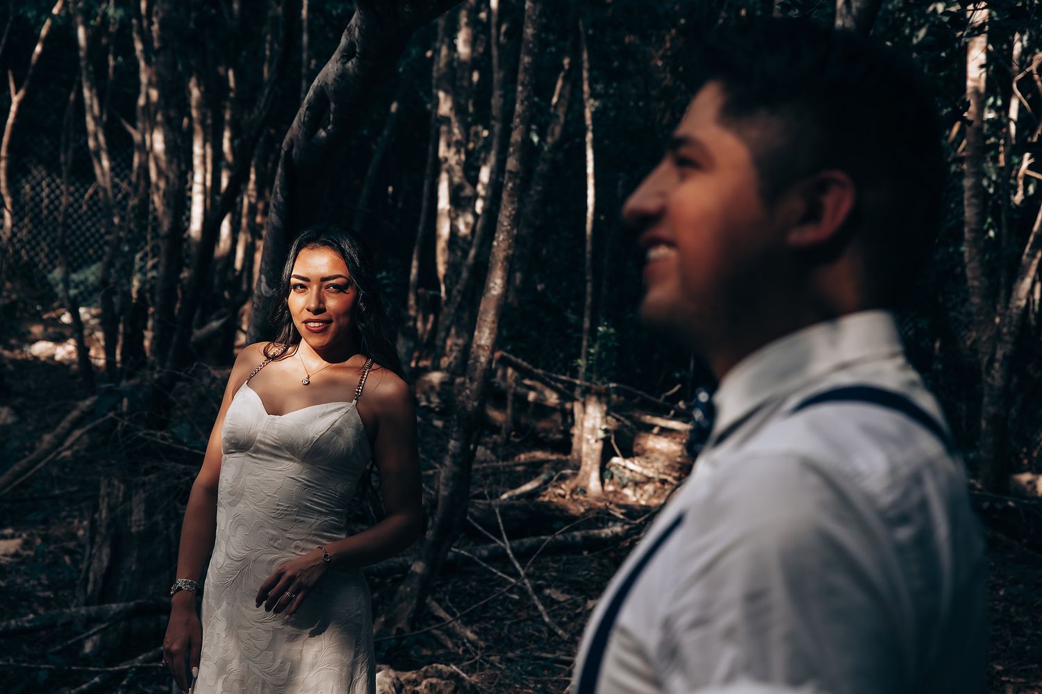 Couple shares romantic moments in a forest setting during their outdoor wedding photoshoot.