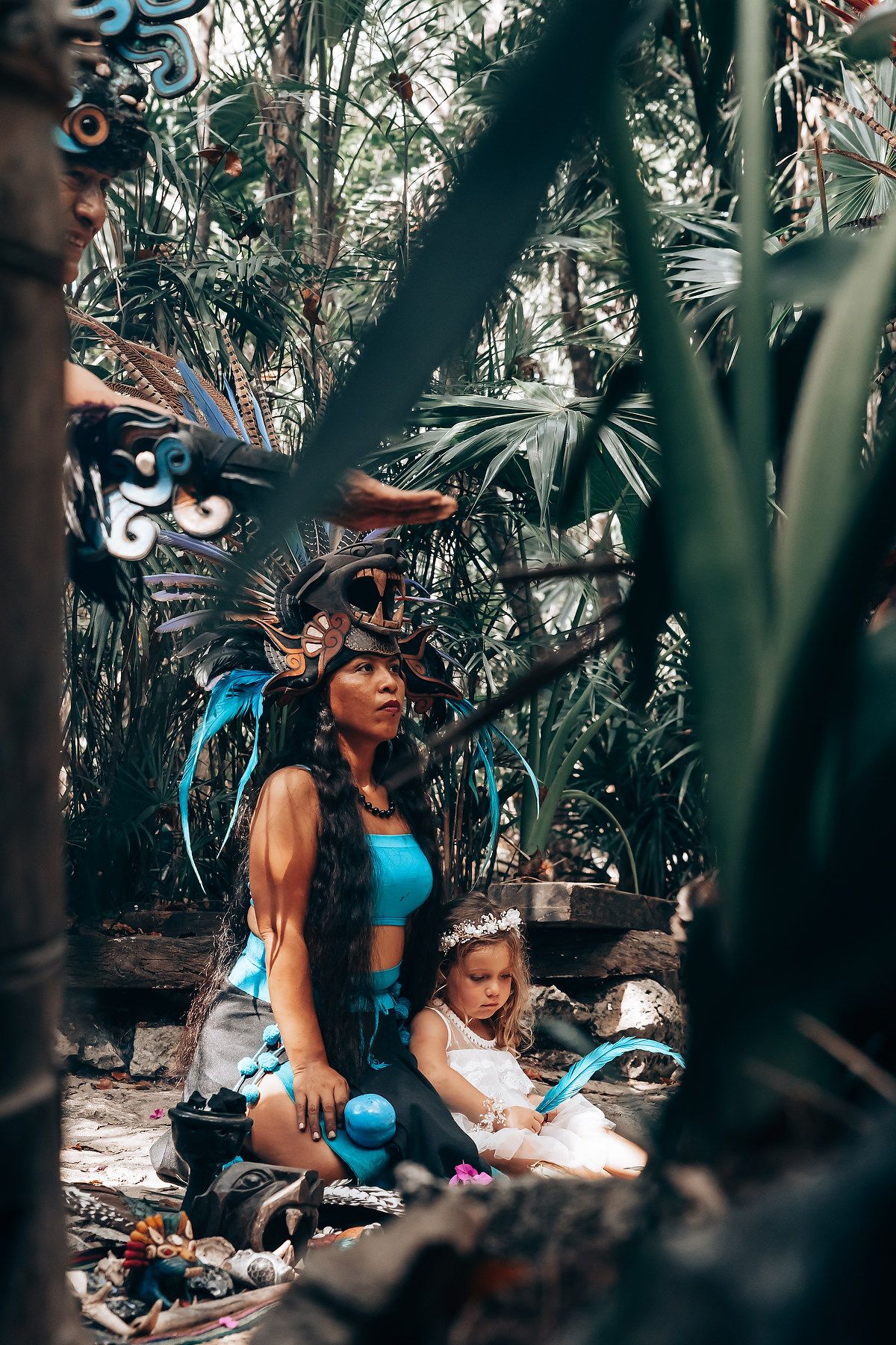 Colorful traditional ceremony taking place in a jungle setting with tropical foliage.