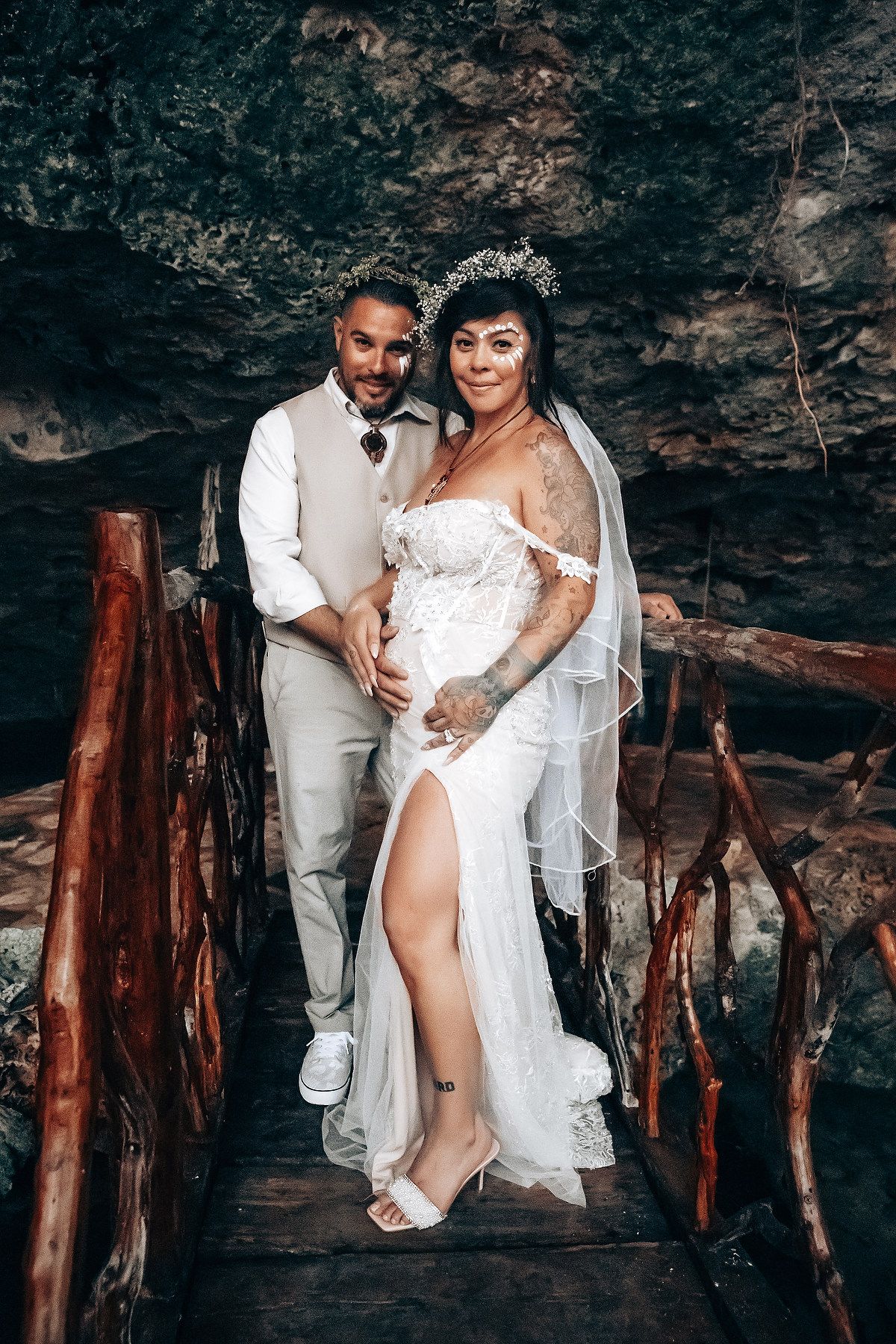 A romantic cave photoshoot featuring a couple in white attire against rocky walls.
