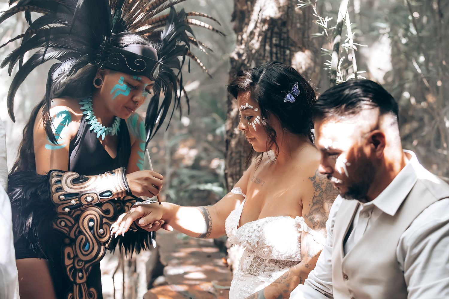 A wedding couple holds hands during an intimate outdoor ceremony in a wooded setting.