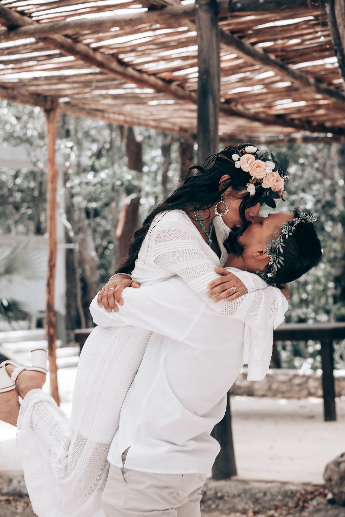 Romantic couple embracing under a wooden pergola with floral decorations.