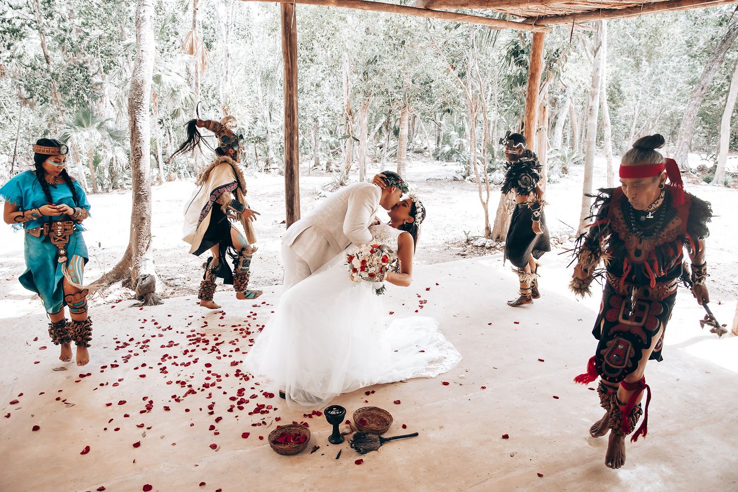 Guests celebrate at an outdoor wedding venue by throwing red rose petals.