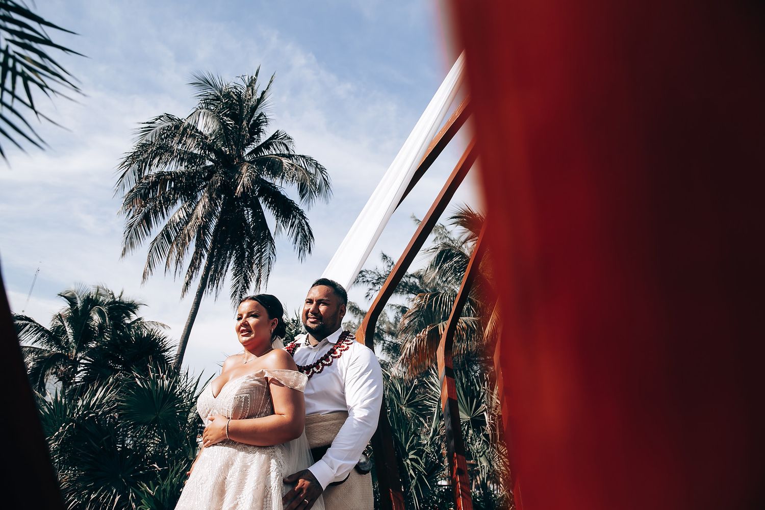 Tropical beach wedding setting with palm trees and ocean views in background.