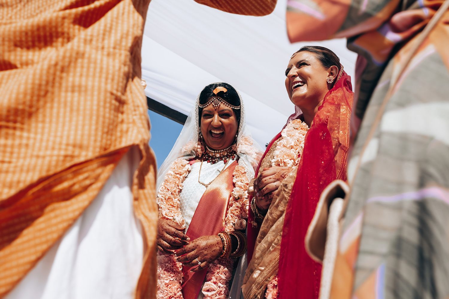 Two people in colorful traditional wedding attire share a joyful moment during a celebration.