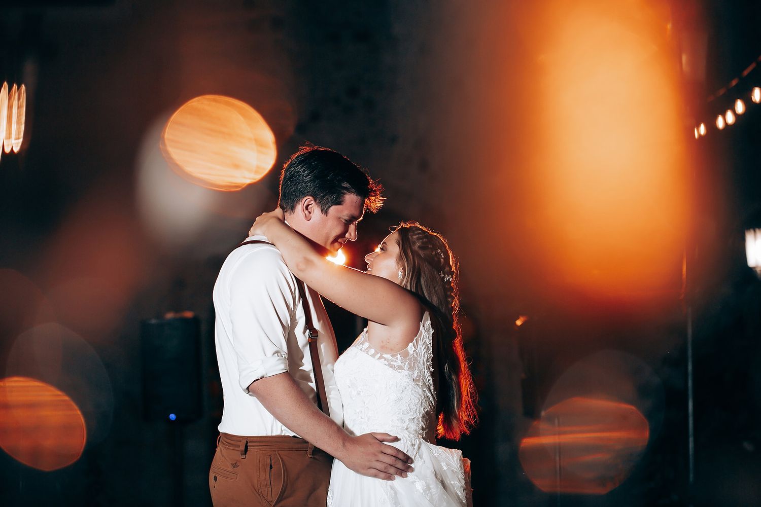 Romantic dance moment captured with warm lighting and bokeh effects in the background.