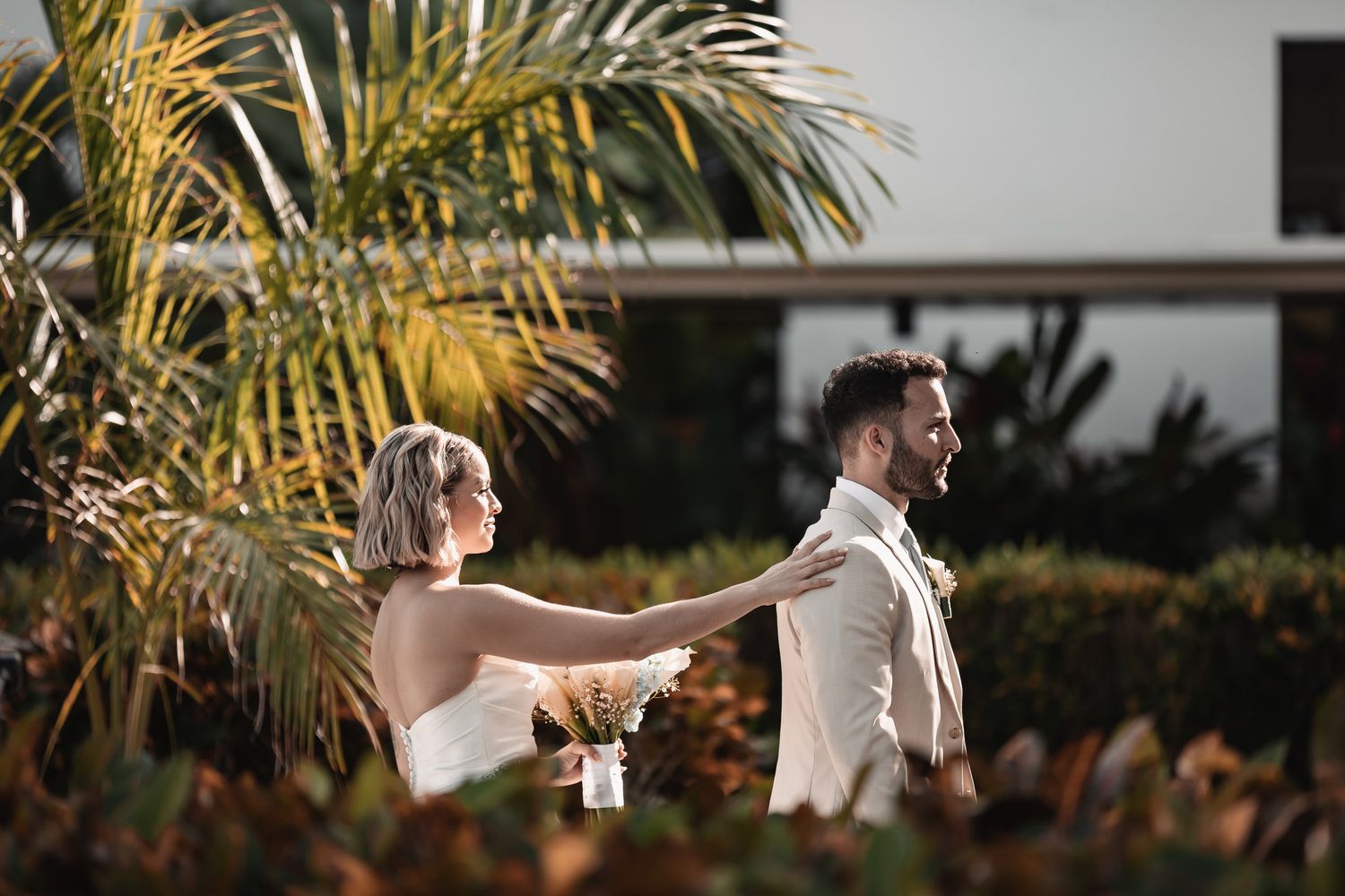 Bride tapping groom on shoulder during outdoor first look reveal.