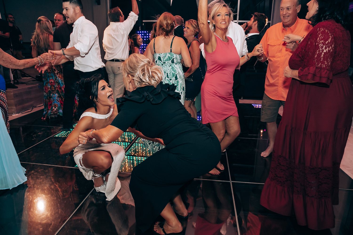 Wedding reception dance floor filled with guests enjoying lively celebration.