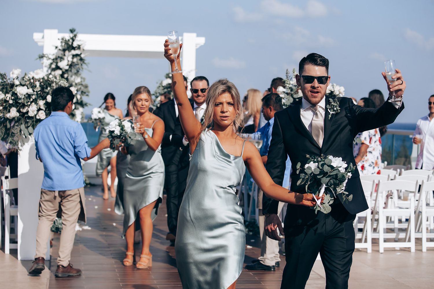 Wedding guests celebrating and walking down the aisle after outdoor beach ceremony.