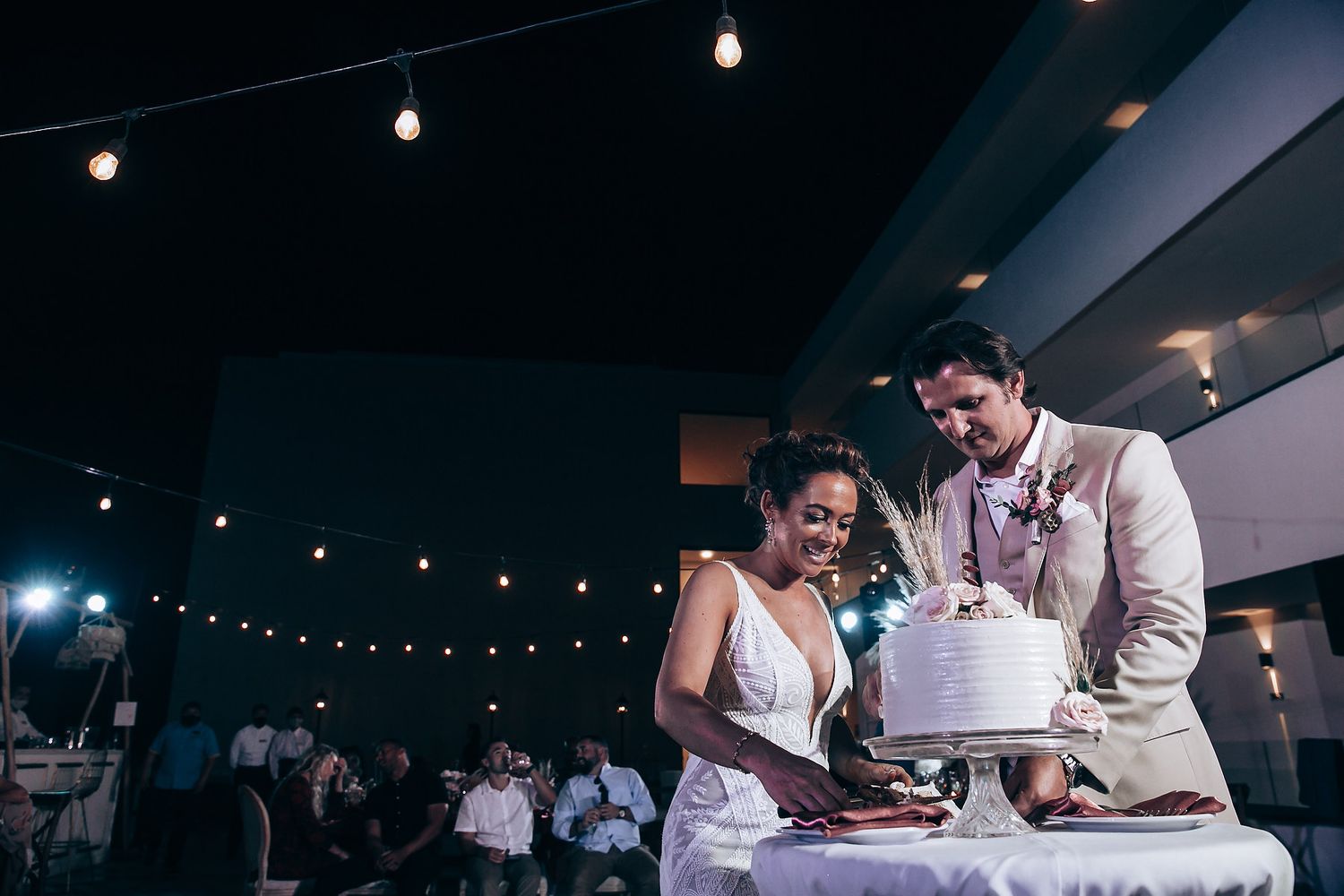 Reception venue with string lights overhead as couple signs wedding documents at night.