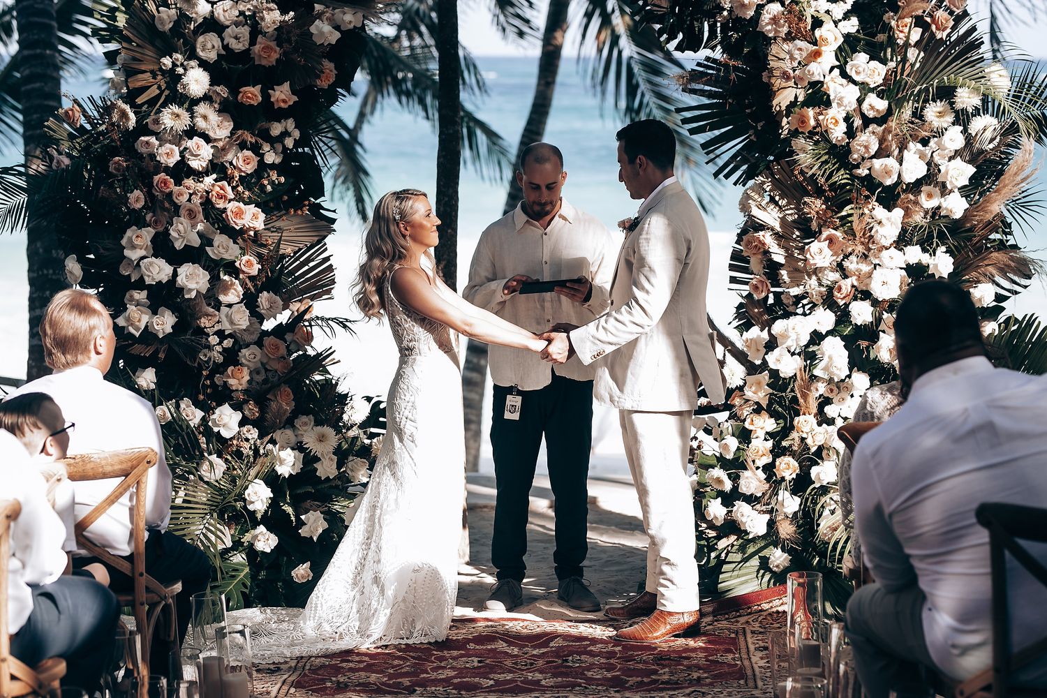 Wedding ceremony moment with floral arch backdrop featuring blush and white roses.
