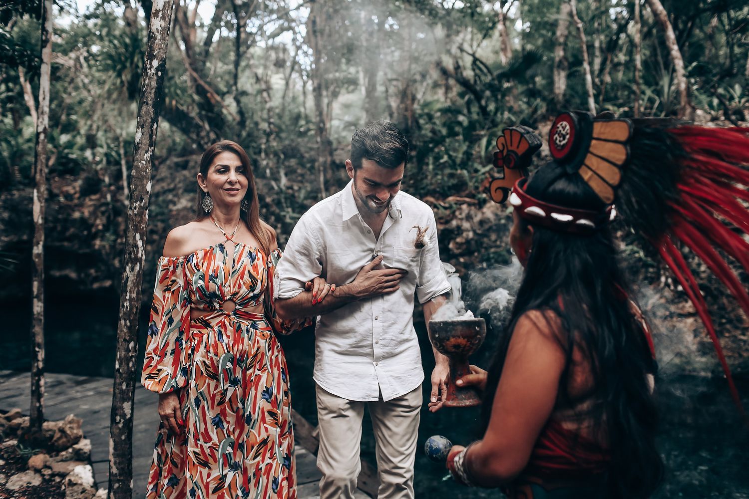 A traditional Indigenous ceremony takes place in a misty forest setting with guests in casual attire.