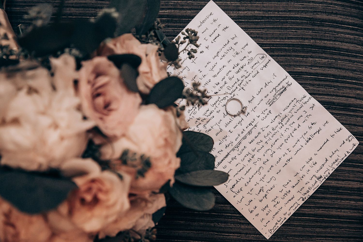 Handwritten wedding vows on white paper cards displayed on dark wooden surface.