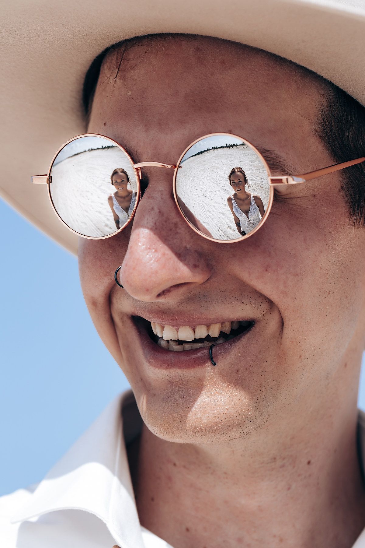 Reflective sunglasses showing a sunny sky and palm trees in the mirrored lenses.