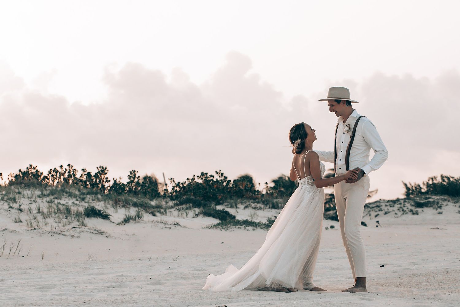 A couple walking along a white sandy beach during their wedding photoshoot.