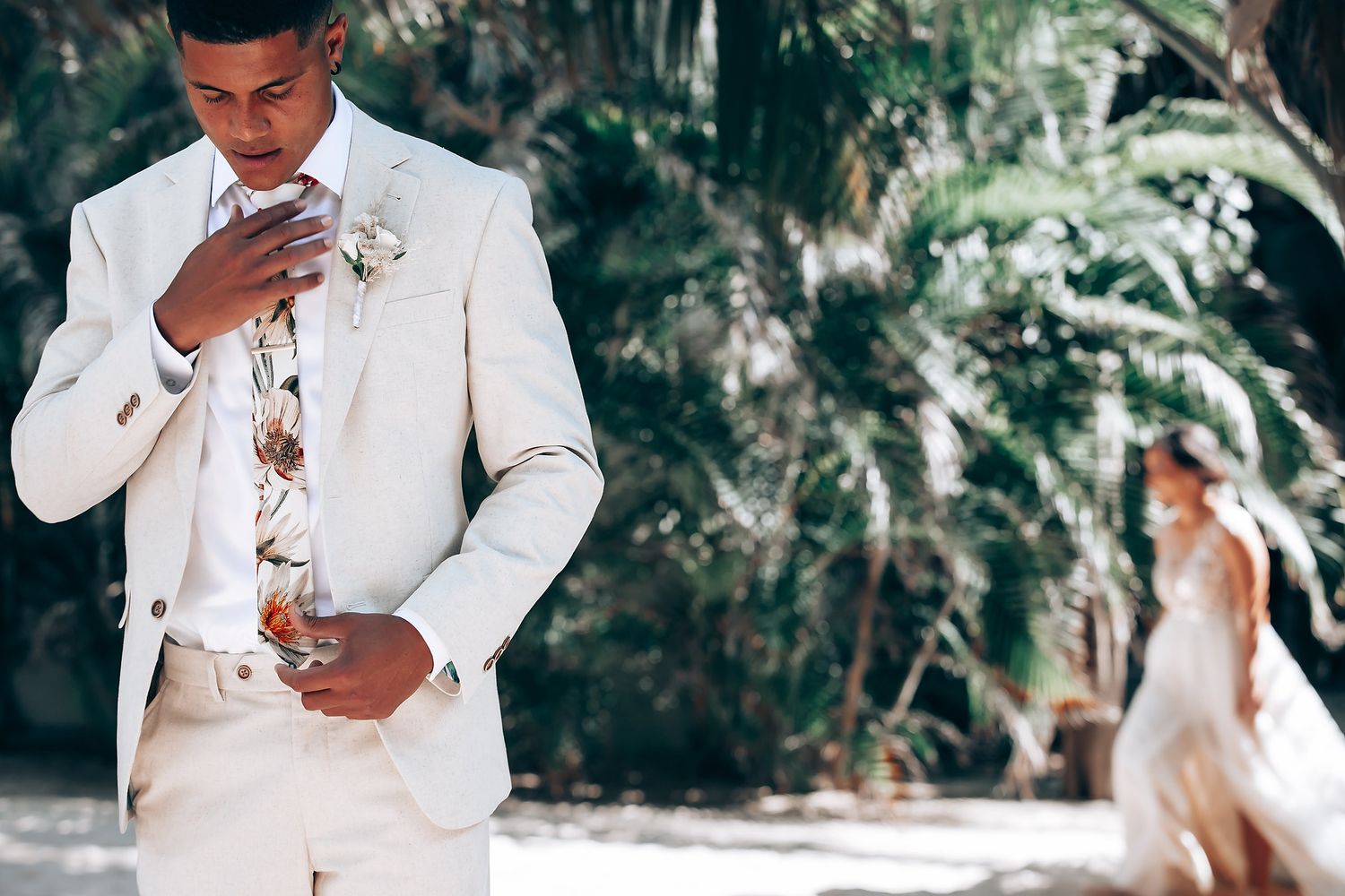 Wedding party in all-white attire posing among tropical palm trees.