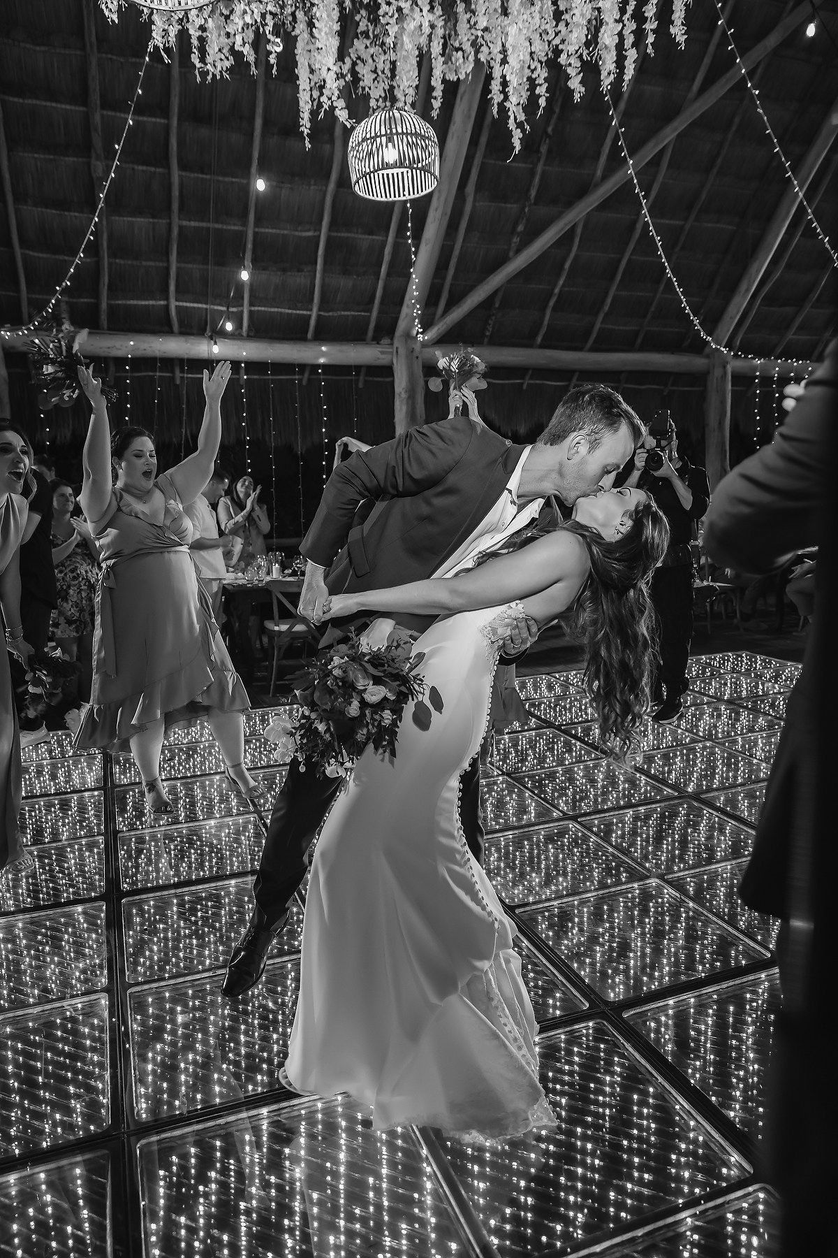 Bride and groom share a romantic dip kiss on a sparkling LED dance floor during their wedding reception.