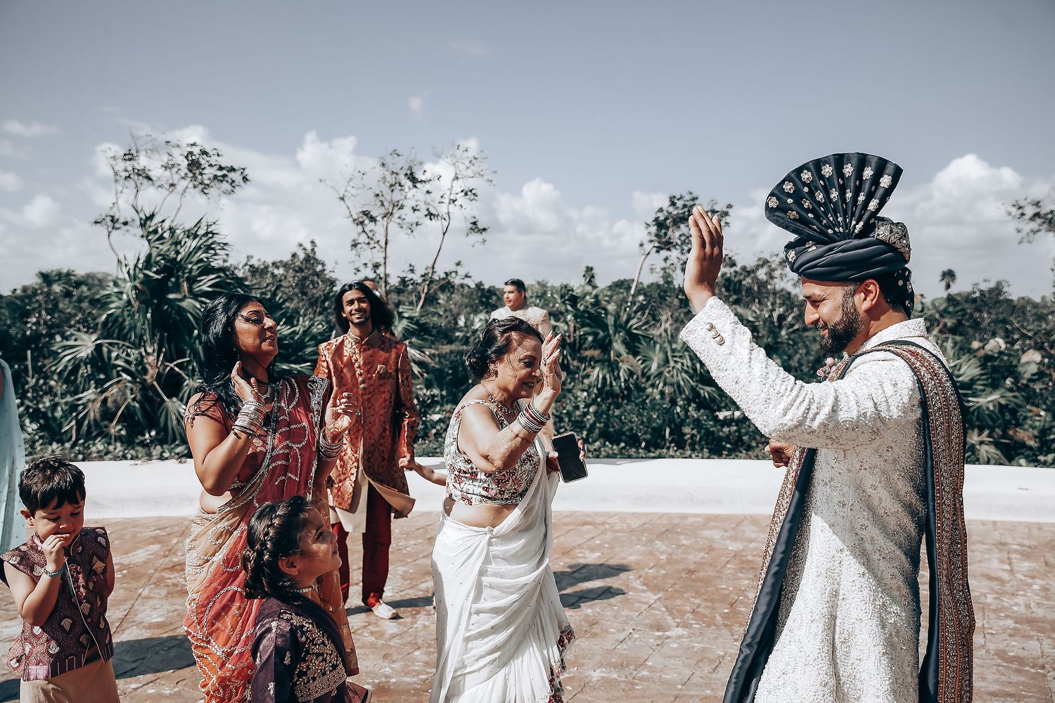 Wedding celebration with guests in traditional attire dancing outdoors.