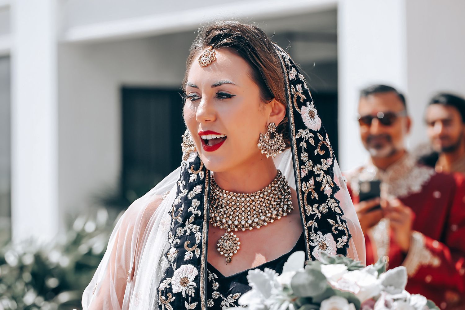 Close up of ornate bridal jewelry and embroidered black and white traditional wedding attire.