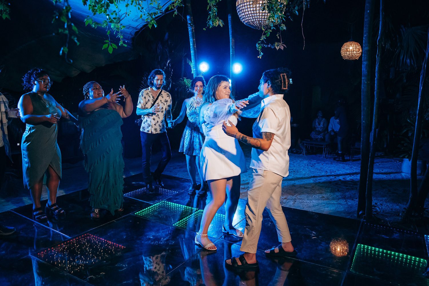 Party guests dancing on an illuminated blue-lit dance floor during an evening celebration.