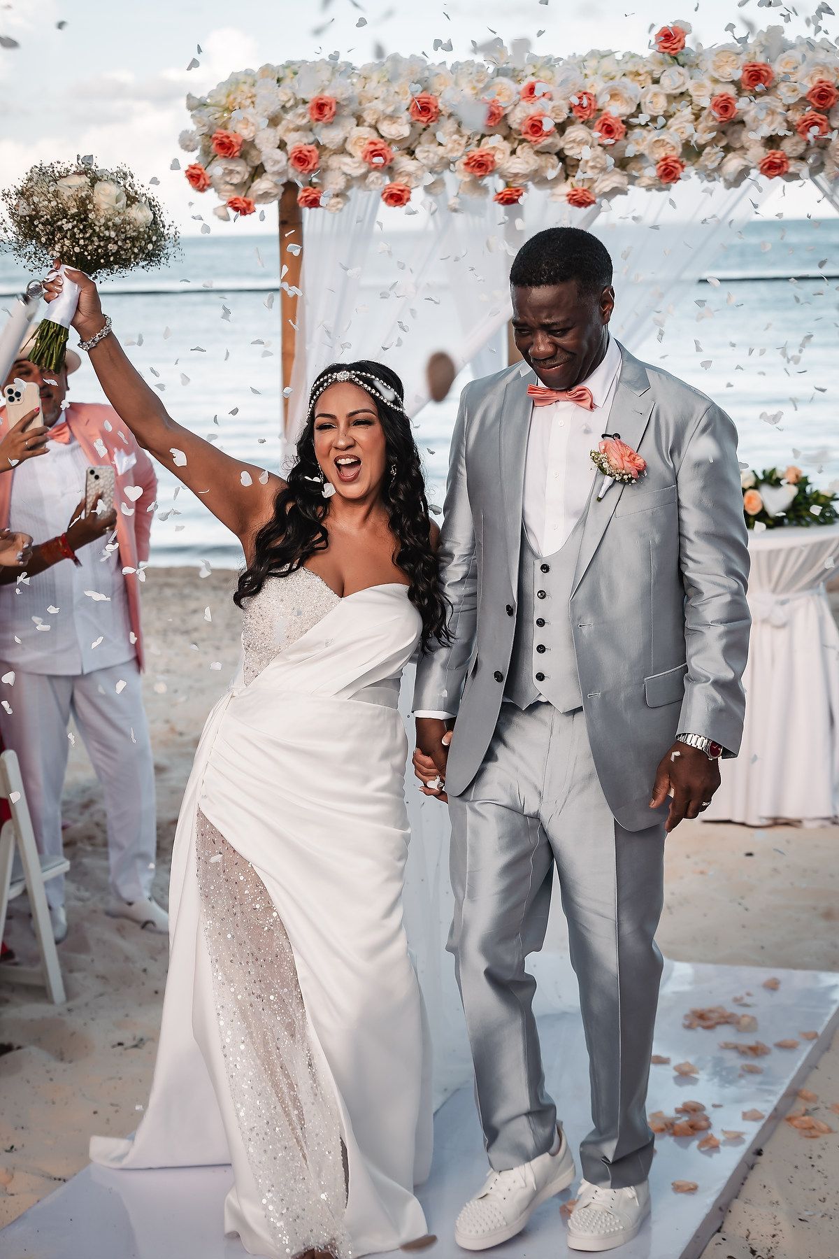 Wedding celebration with confetti flying as couple dances in white dress and light gray suit with matching sneakers.