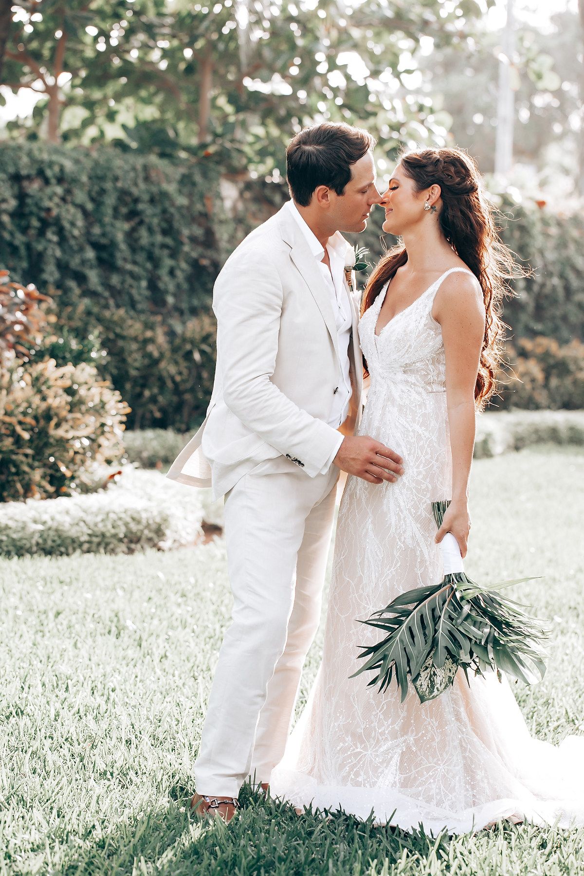 Romantic wedding photoshoot in an all-white garden setting with lush greenery.