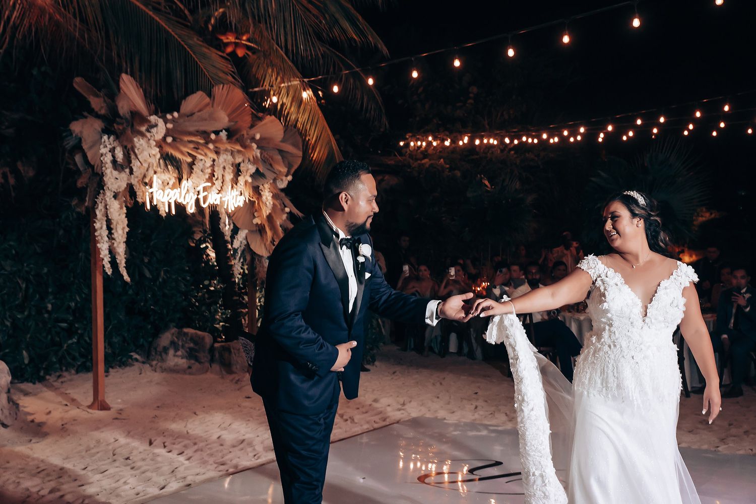 Elegant beach wedding celebration with string lights and tropical decor.