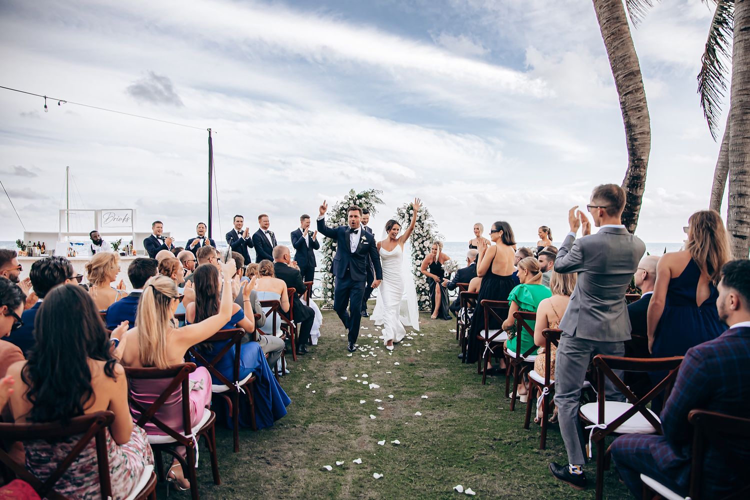 Panoramic view of wedding guests seated at an outdoor oceanfront ceremony.