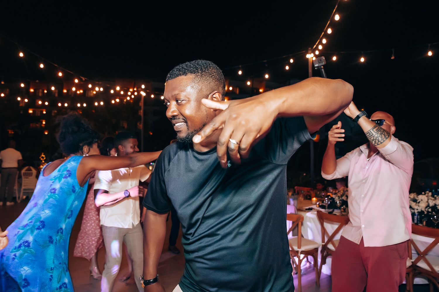 Evening wedding reception with string lights and dancing guests creating a festive atmosphere.