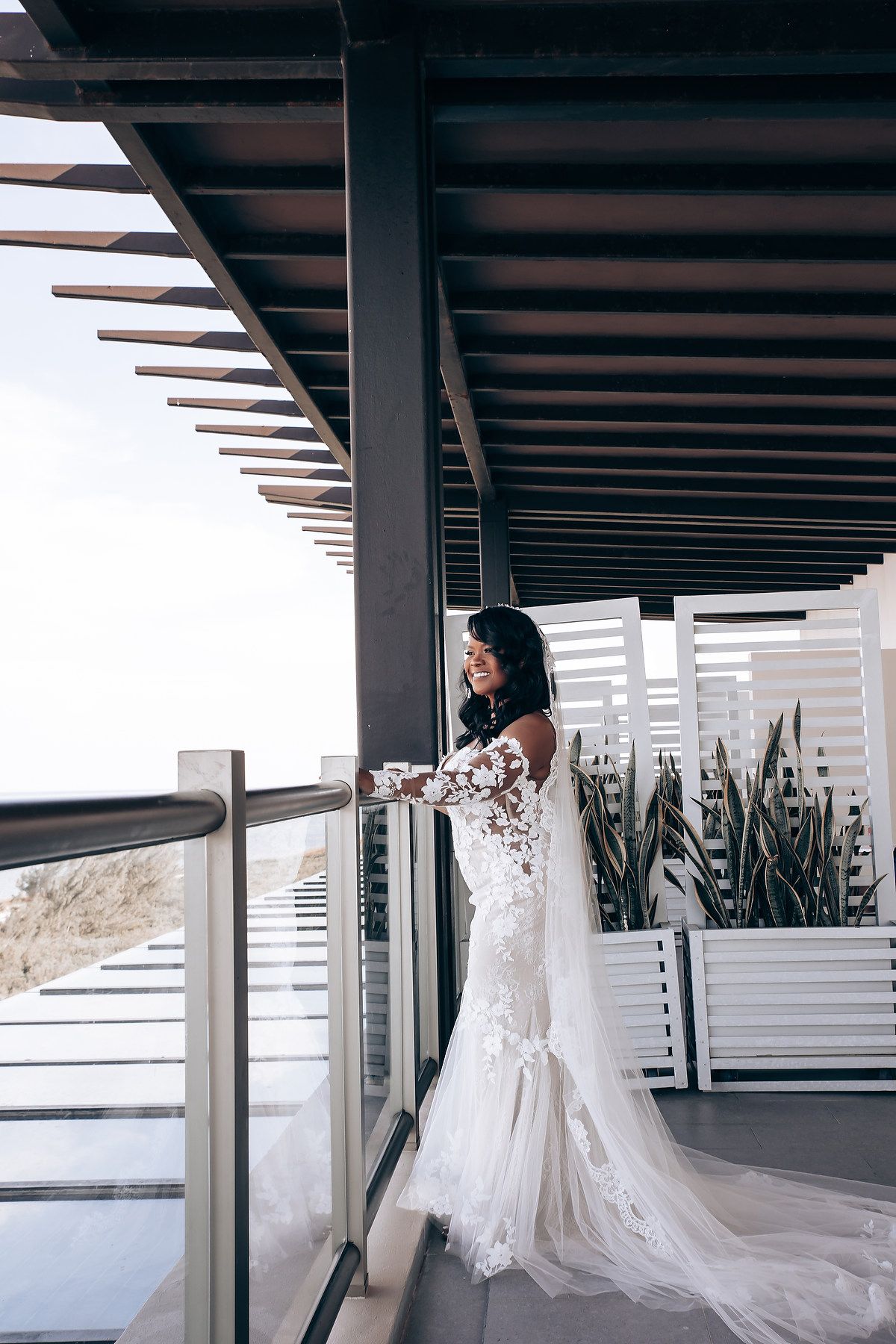 Dramatic architectural setting with wooden beams and white wedding dress silhouette against natural light.