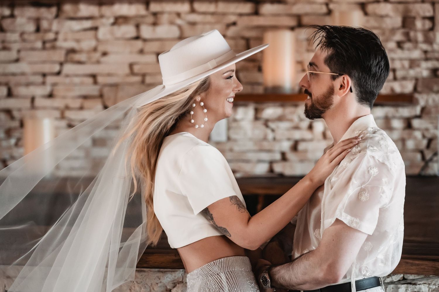 Romantic wedding couple shares intimate moments against a rustic brick wall backdrop.