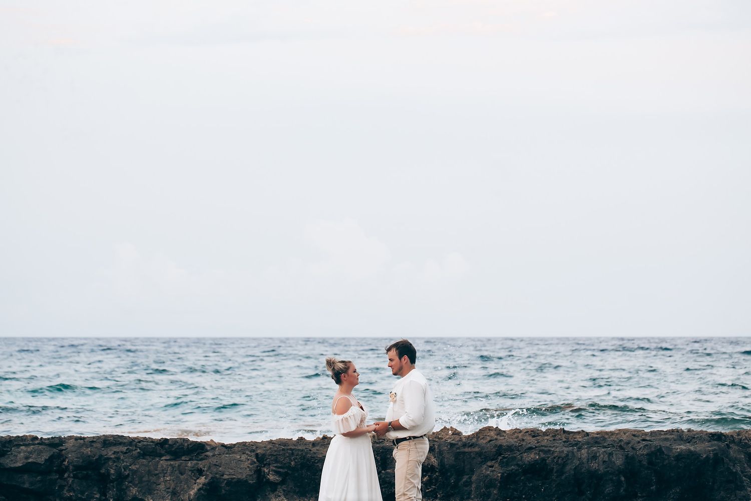 Oceanfront wedding celebration with waves crashing against rocky coastline.