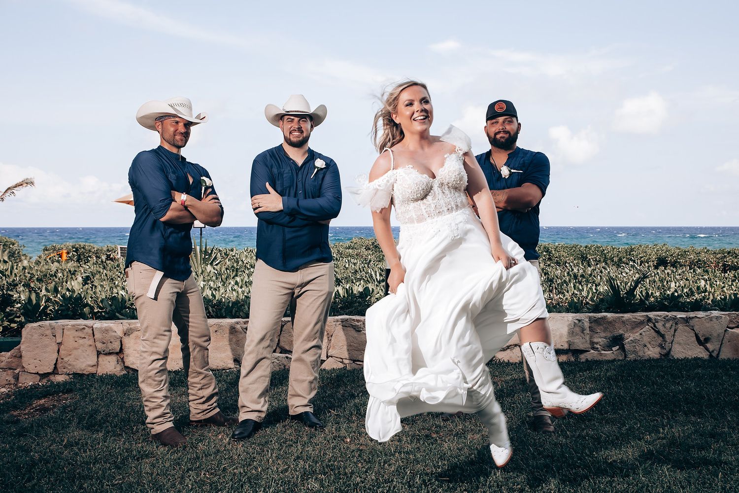 Wedding party celebrating on a scenic oceanfront lawn with tropical landscape.